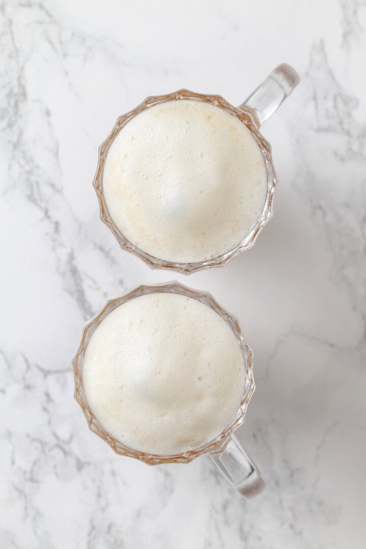 This cozy London Fog recipe blends fragrant Earl Grey tea, vanilla and creamy vegan milk into a sweet café-style latte you can make at home! Frothed milk added to glass mugs for London fog recipe.