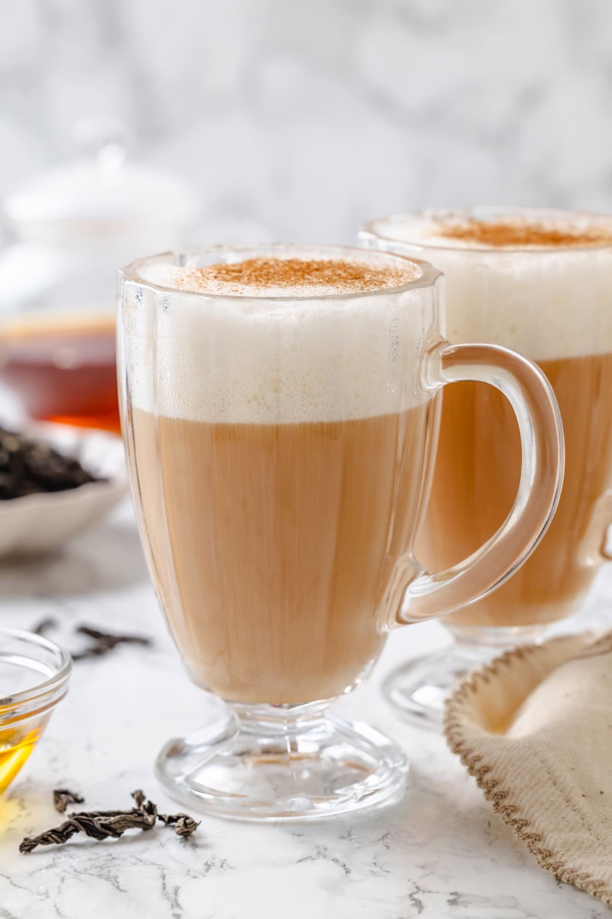 This cozy London Fog recipe blends fragrant Earl Grey tea, vanilla and creamy vegan milk into a sweet café-style latte you can make at home! Two glass mugs filled with frothy London fog latte.