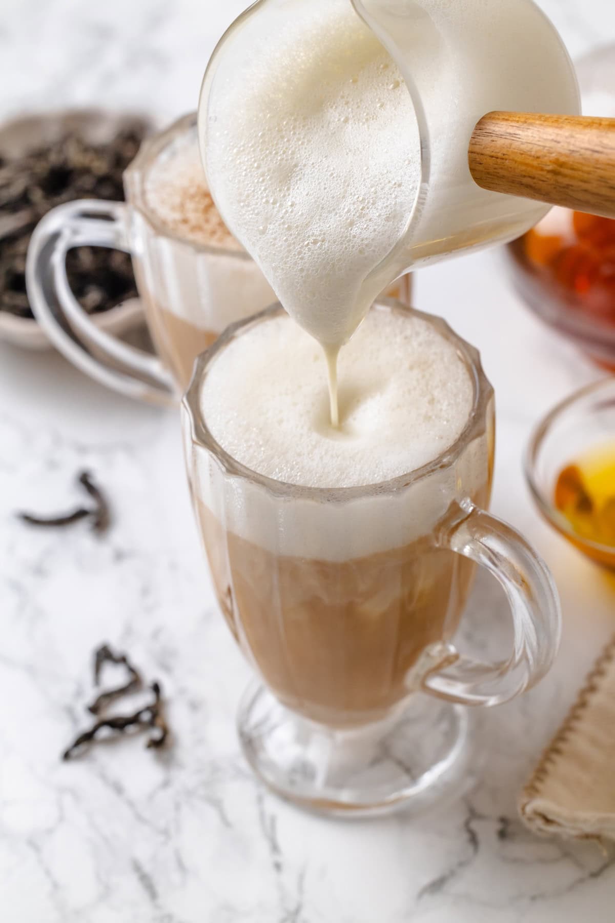 This cozy London Fog recipe blends fragrant Earl Grey tea, vanilla and creamy vegan milk into a sweet café-style latte you can make at home! Pouring frothed milk into London fog latte.