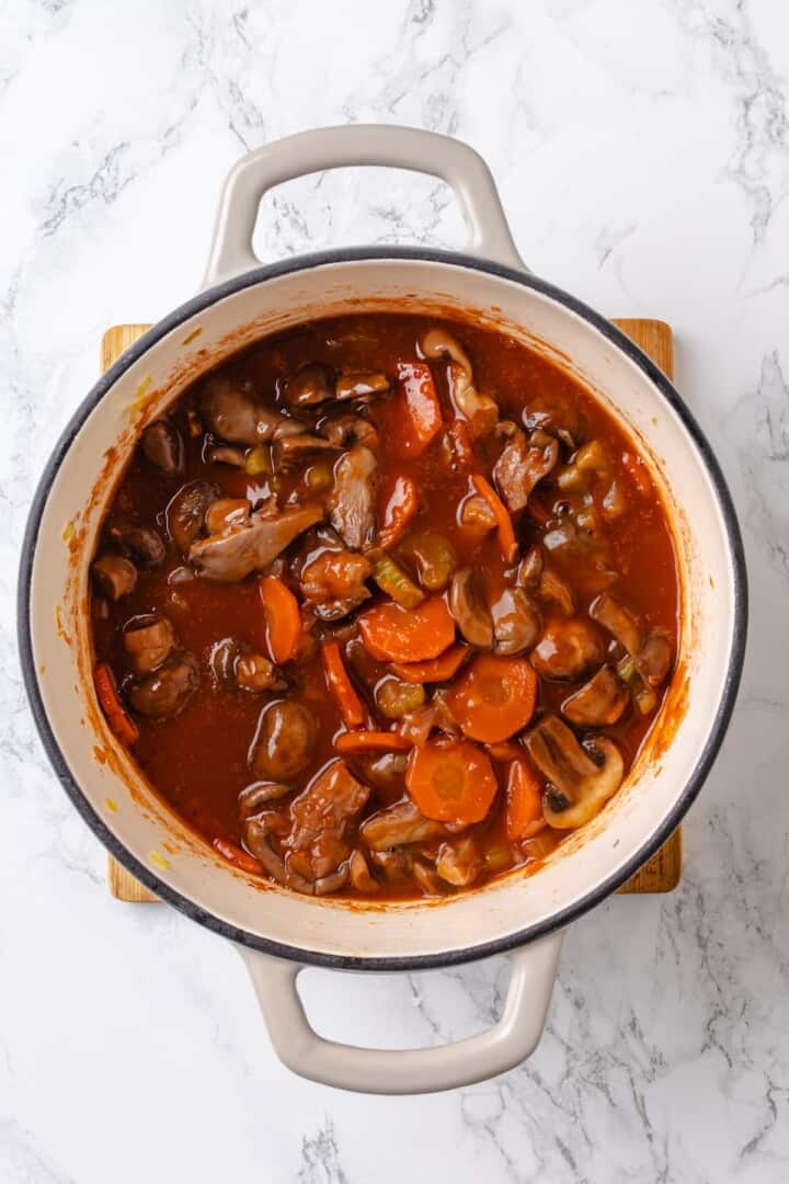 Mushroom bourguignon is a rich, savoury vegan stew simmered in red wine with herbs and meaty mushrooms. A cozy yet elegant meal! Mushroom bourguignon in large pot.