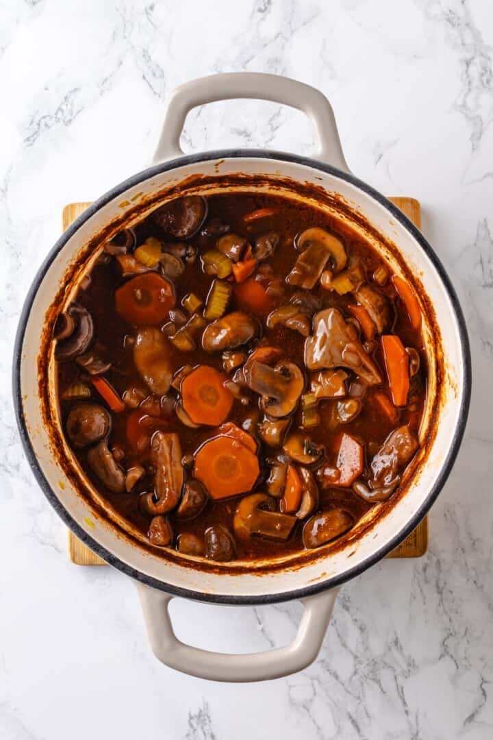 Mushroom bourguignon is a rich, savoury vegan stew simmered in red wine with herbs and meaty mushrooms. A cozy yet elegant meal! Mushroom bourguignon in Dutch oven.