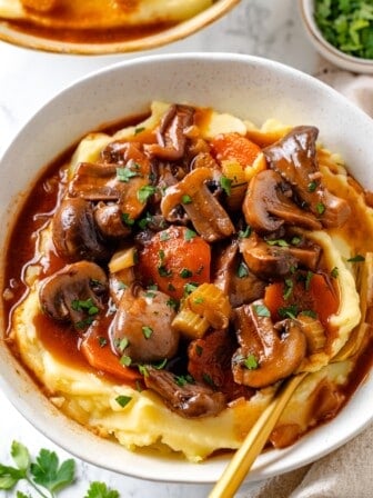 Bowl of mushroom bourguignon served over mashed potatoes.