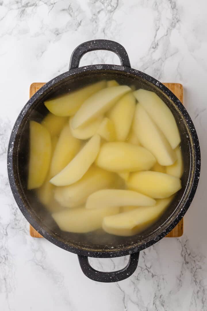 These homemade tater tots are crispy outside, fluffy inside and made with real potatoes. Bake, fry, air fry or freeze them for later! Potatoes in pot of water.