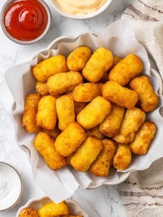 Bowl of crispy homemade tater tots with bowl of ketchup.
