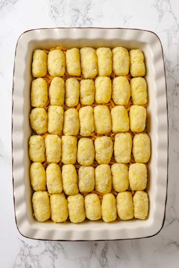 This vegan tater tot casserole recipe is creamy, hearty and topped with crispy homemade tots. A cozy, crowd-pleasing comfort food dinner! Vegan tater tot casserole in pan before baking.