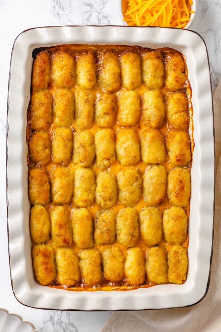 This vegan tater tot casserole recipe is creamy, hearty and topped with crispy homemade tots. A cozy, crowd-pleasing comfort food dinner! Vegan tater tot casserole in baking dish.