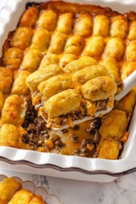 Lifting portion of vegan tater tot casserole from pan.