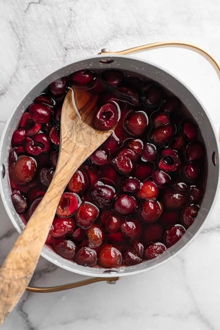 Stirring cherries in saucepan for syrup.