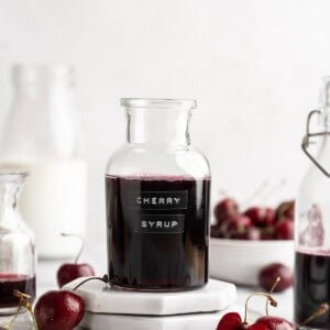 Bottle of cherry syrup with fresh cherries.