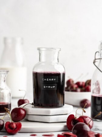 Bottle of cherry syrup with fresh cherries.