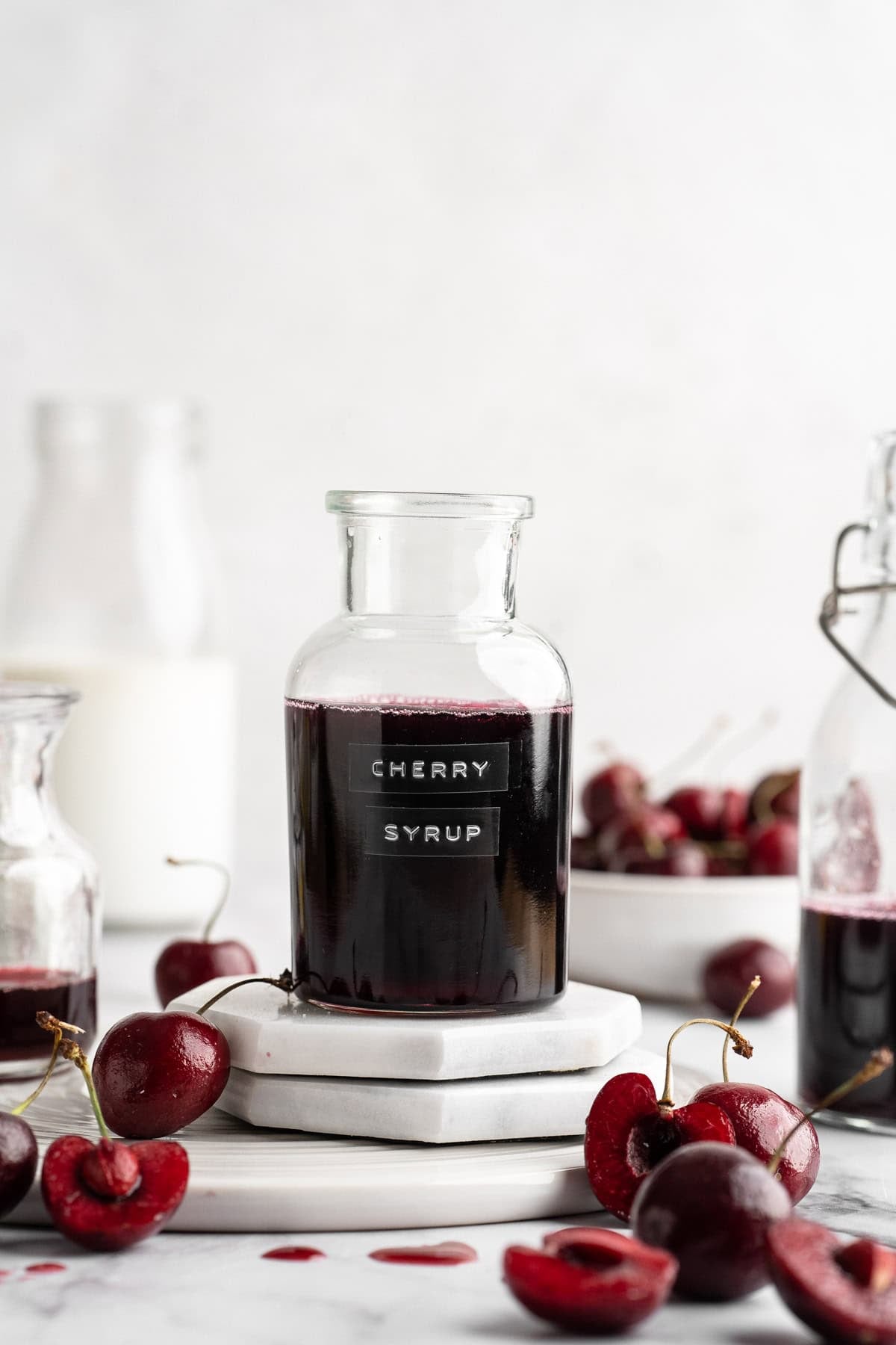 Bottle of cherry syrup with fresh cherries.