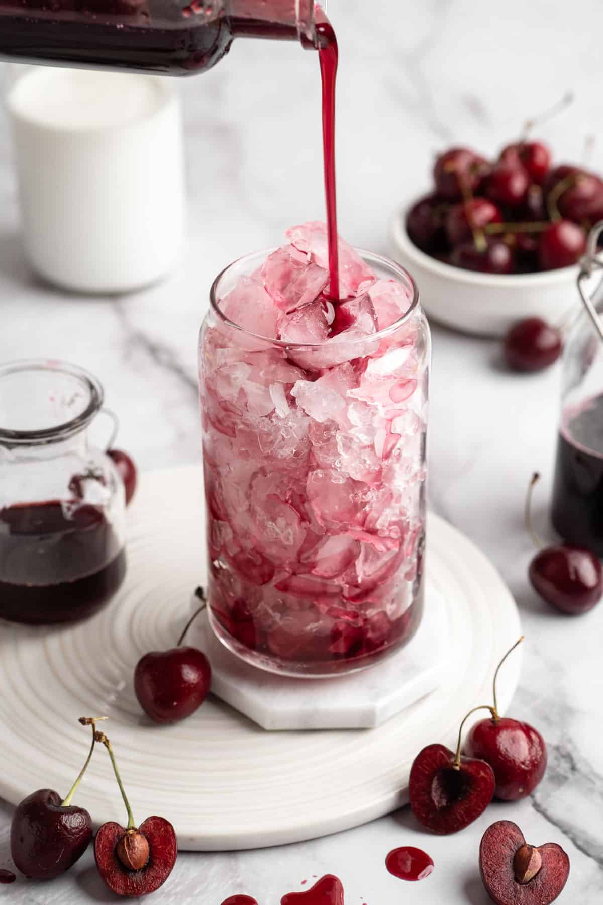 Pouring cherry syrup into glass of ice.