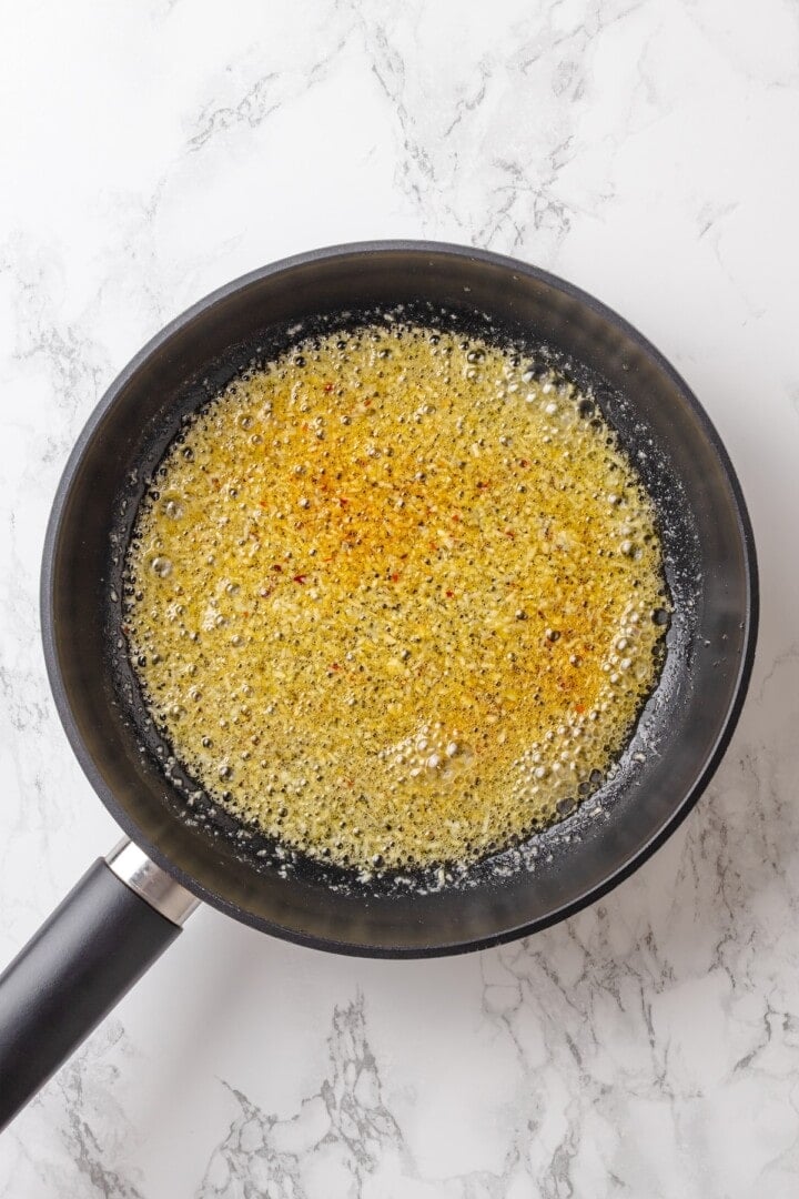 These vegan garlic noodles deliver bold, buttery garlic flavour in a quick, satisfying dish that’s ready in just 20 minutes! Garlic cooking in skillet with oil and butter.