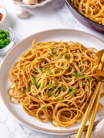 Plate of garlic noodles with green onions for garnish.