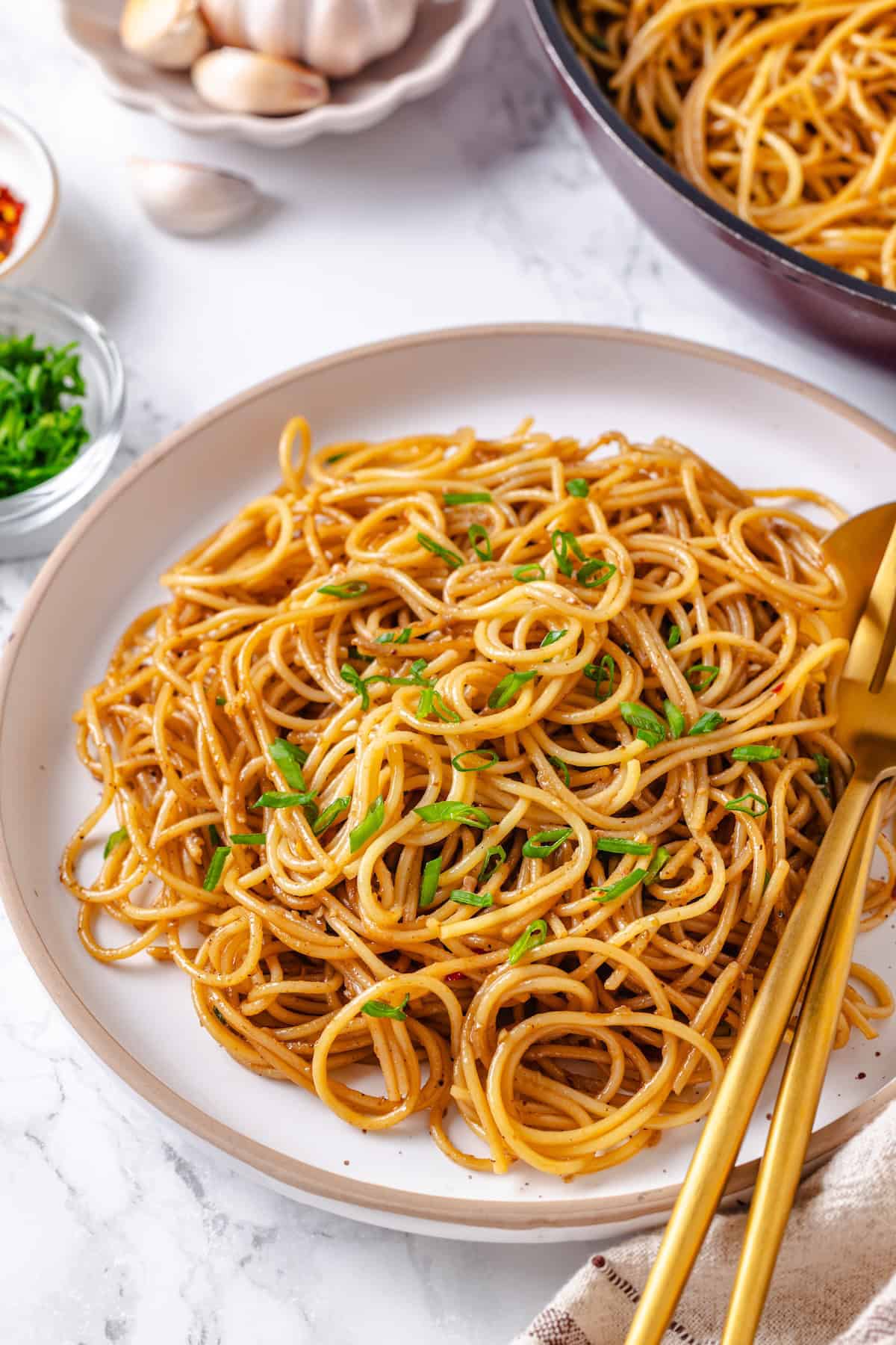 These vegan garlic noodles deliver bold, buttery garlic flavour in a quick, satisfying dish that’s ready in just 20 minutes! Plate of garlic noodles with green onions for garnish.