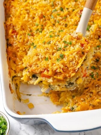 Lifting portion of loaded hashbrown casserole from dish.