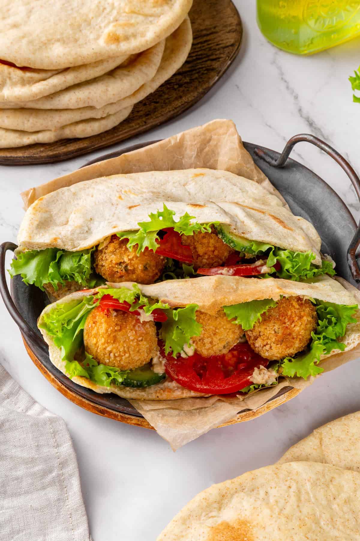 Tender and warm, with a perfect pocket in the middle, this easy homemade pita bread recipe gives your wraps, dips and sandwiches an upgrade! Two pita bread halves stuffed with falafel and veggies.