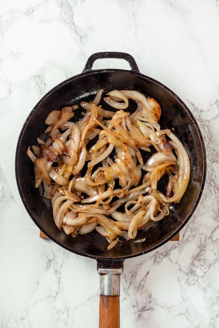 Savory, hearty and full of umami flavor, this homemade vegan steak is made with seitan for a protein-packed plant-based main dish! Onions cooking in skillet.