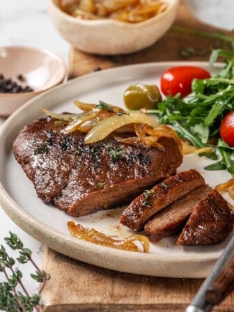 Sliced vegan steak on plate with salad.
