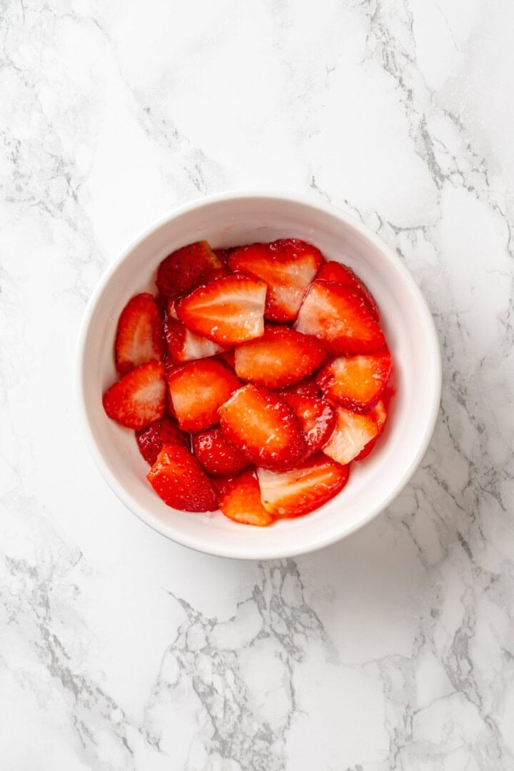 Golden, custardy, and filled with jammy berries and vanilla cream cheese, this vegan stuffed French toast turns brunch into something special! Strawberries macerating in bowl.