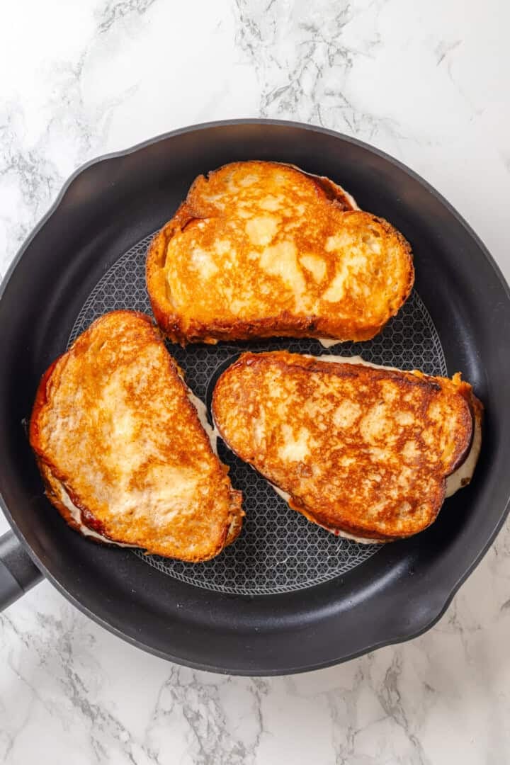 Golden, custardy, and filled with jammy berries and vanilla cream cheese, this vegan stuffed French toast turns brunch into something special! Stuffed French toast cooking in skillet.