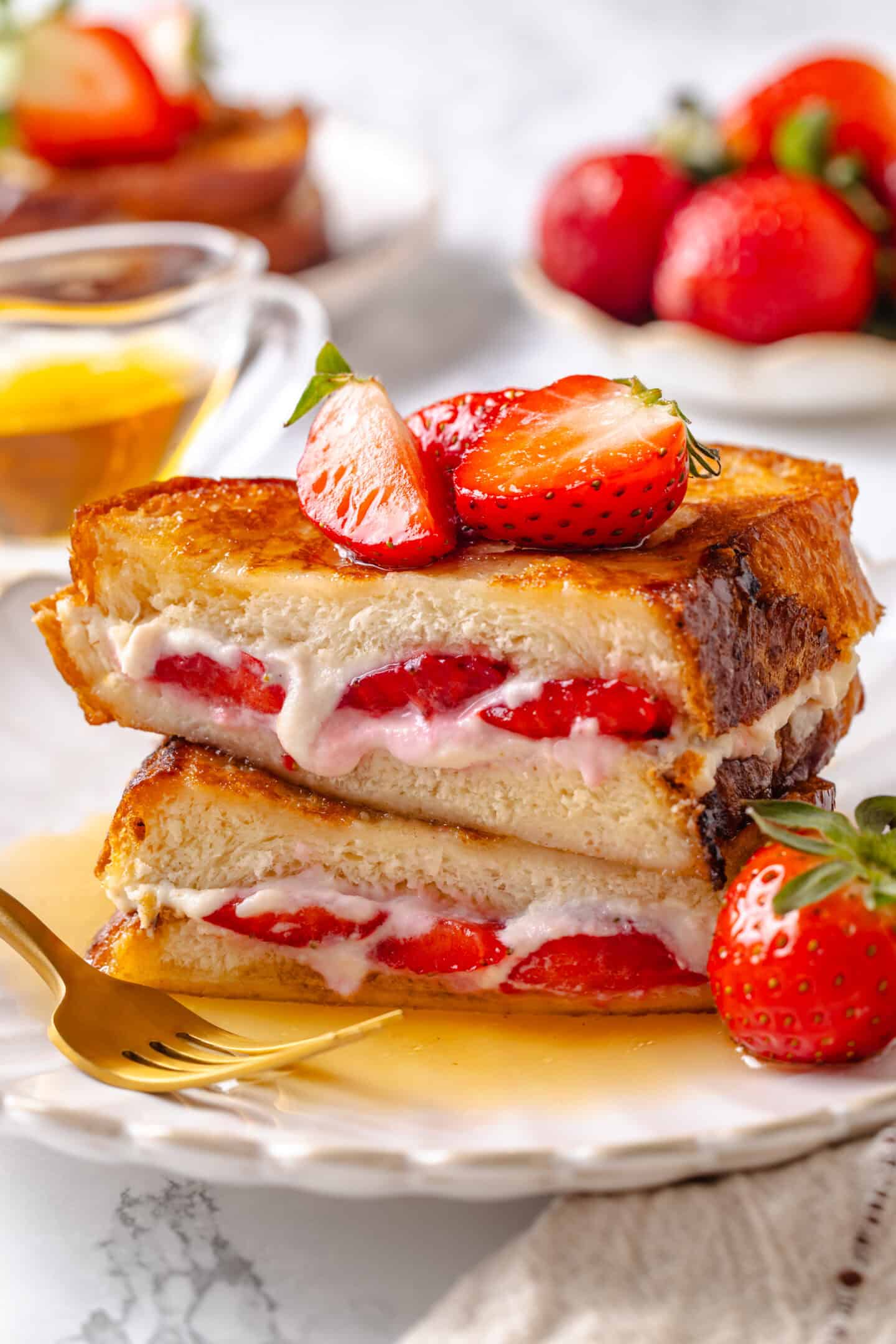 Golden, custardy, and filled with jammy berries and vanilla cream cheese, this vegan stuffed French toast turns brunch into something special! Plate of stuffed French toast with strawberries and cream cheese.