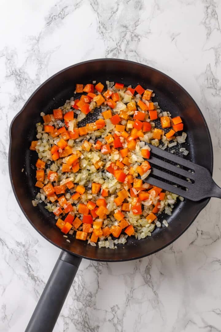 Onions and red bell peppers in skillet.