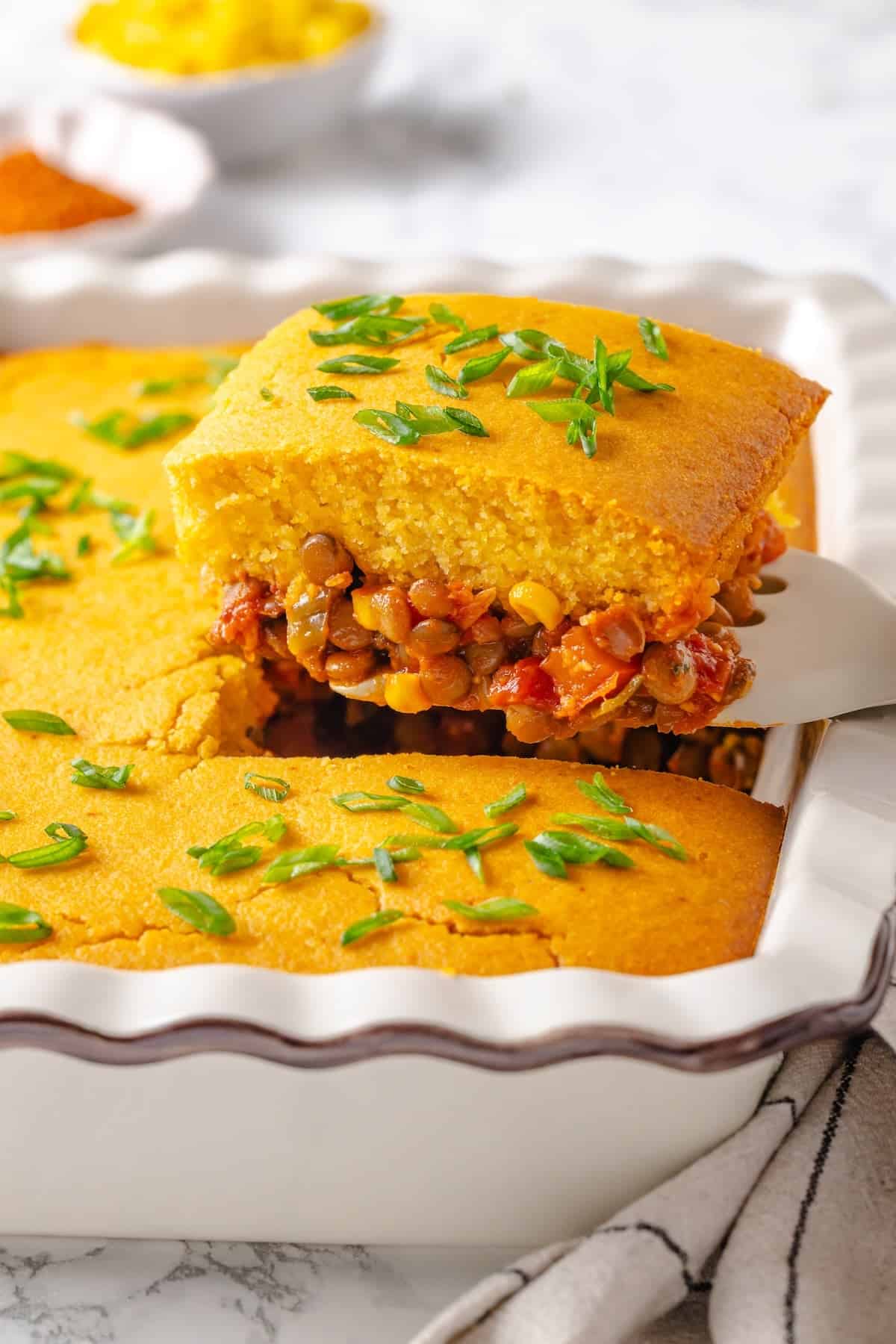 Lifting portion of tamale casserole from baking dish.