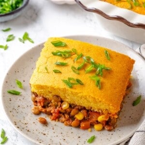 Vegan tamale casserole on plate with green onions for garnish.