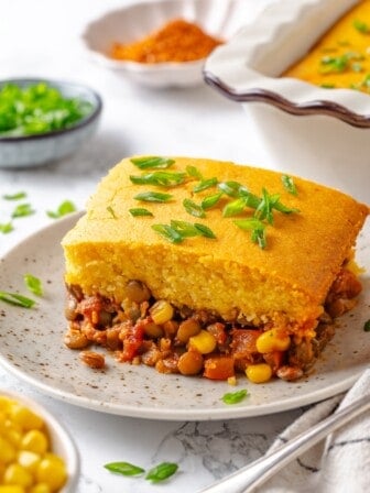 Tamale casserole portion on plate with green onions for garnish.