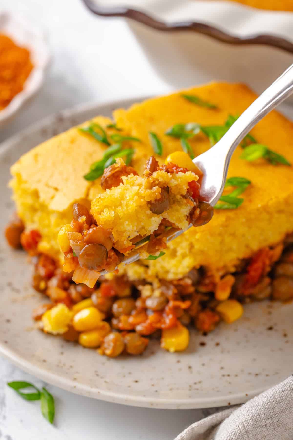 Forkful of tamale casserole held over plate.