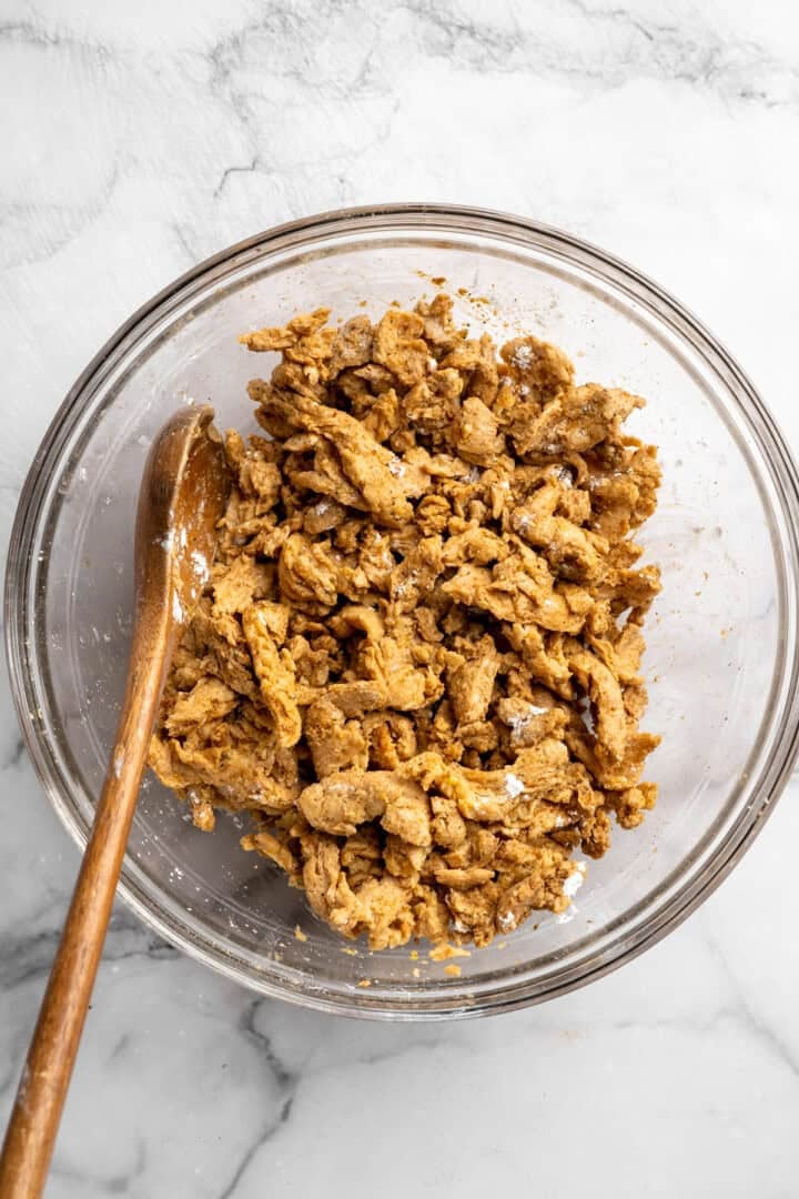 A little bit crispy, budget-friendly and packed with bold flavour, these BBQ soy curls are an easy vegan staple you’ll make again and again! Stirring soy curls with marinade.