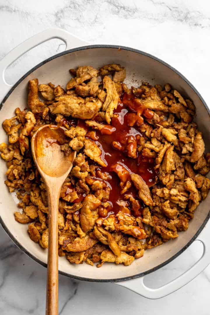 A little bit crispy, budget-friendly and packed with bold flavour, these BBQ soy curls are an easy vegan staple you’ll make again and again! BBQ sauce added to skillet of soy curls.