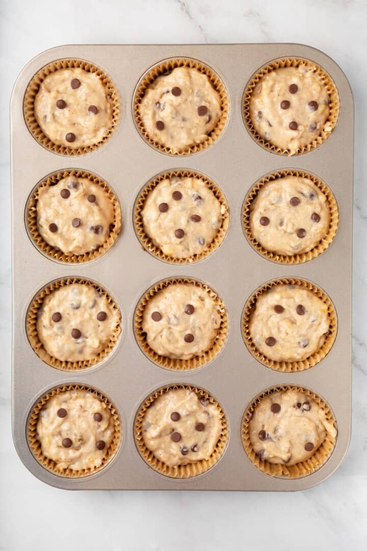 These vegan banana chocolate chip muffins bake up soft, moist and full of chocolate and crunchy walnuts. Perfect for breakfast and snacks! Batter for banana chocolate chip muffins in pan.