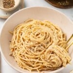 Bowl of cacio e pepe with spoon and fork.