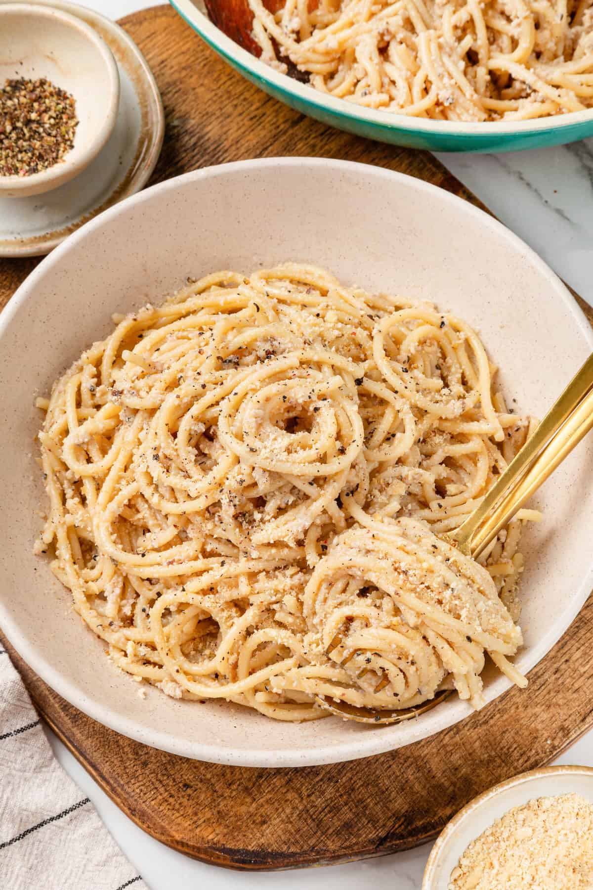 Bowl of cacio e pepe on wooden board.