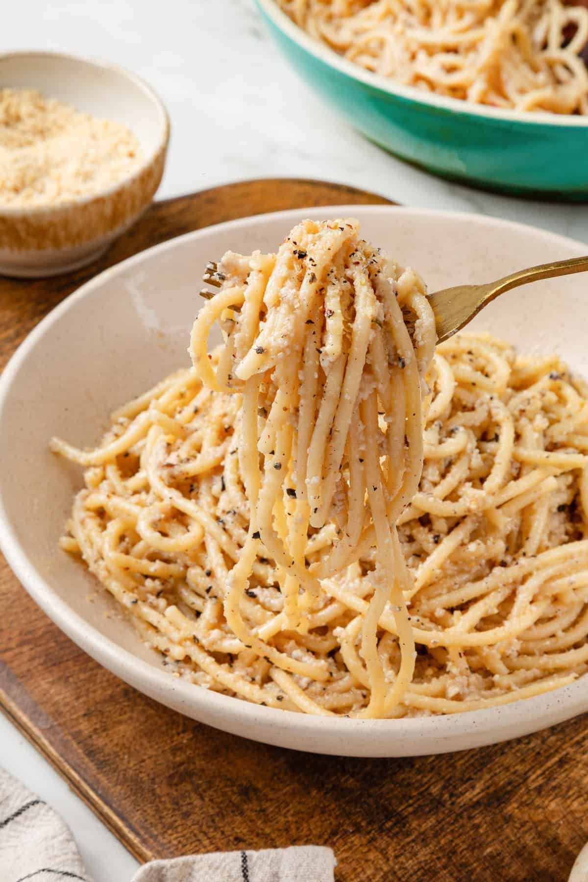 Forkful of vegan cacio e pepe held over bowl.