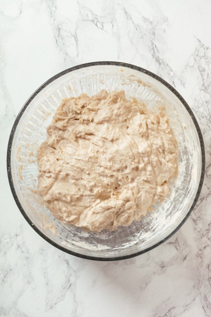 This Dutch oven sourdough bread gives you a bakery-style loaf with a crisp, golden crust and chewy interior. It's easier than you think! Sourdough bread dough in bowl.