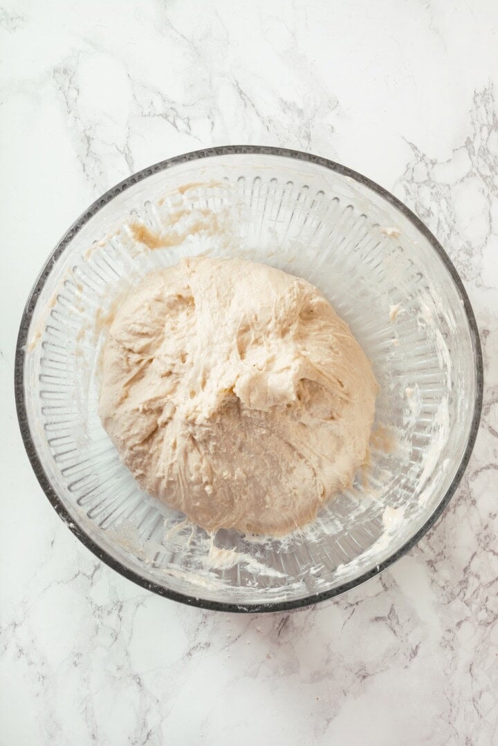 This Dutch oven sourdough bread gives you a bakery-style loaf with a crisp, golden crust and chewy interior. It's easier than you think! Sourdough dough in bowl.