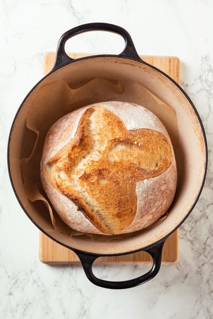 This Dutch oven sourdough bread gives you a bakery-style loaf with a crisp, golden crust and chewy interior. It's easier than you think! Loaf of sourdough bread in Dutch oven.
