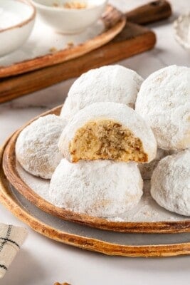 Plate of Mexican wedding cookies, with one bitten to show interior.