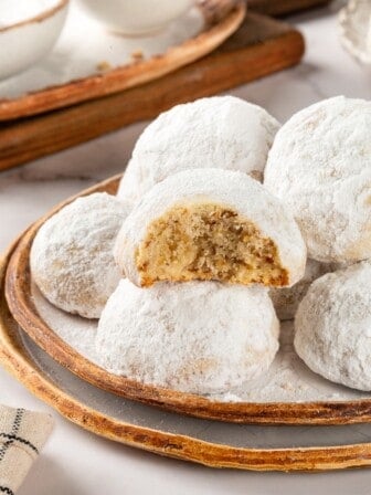 Plate of Mexican wedding cookies, with one bitten to show interior.