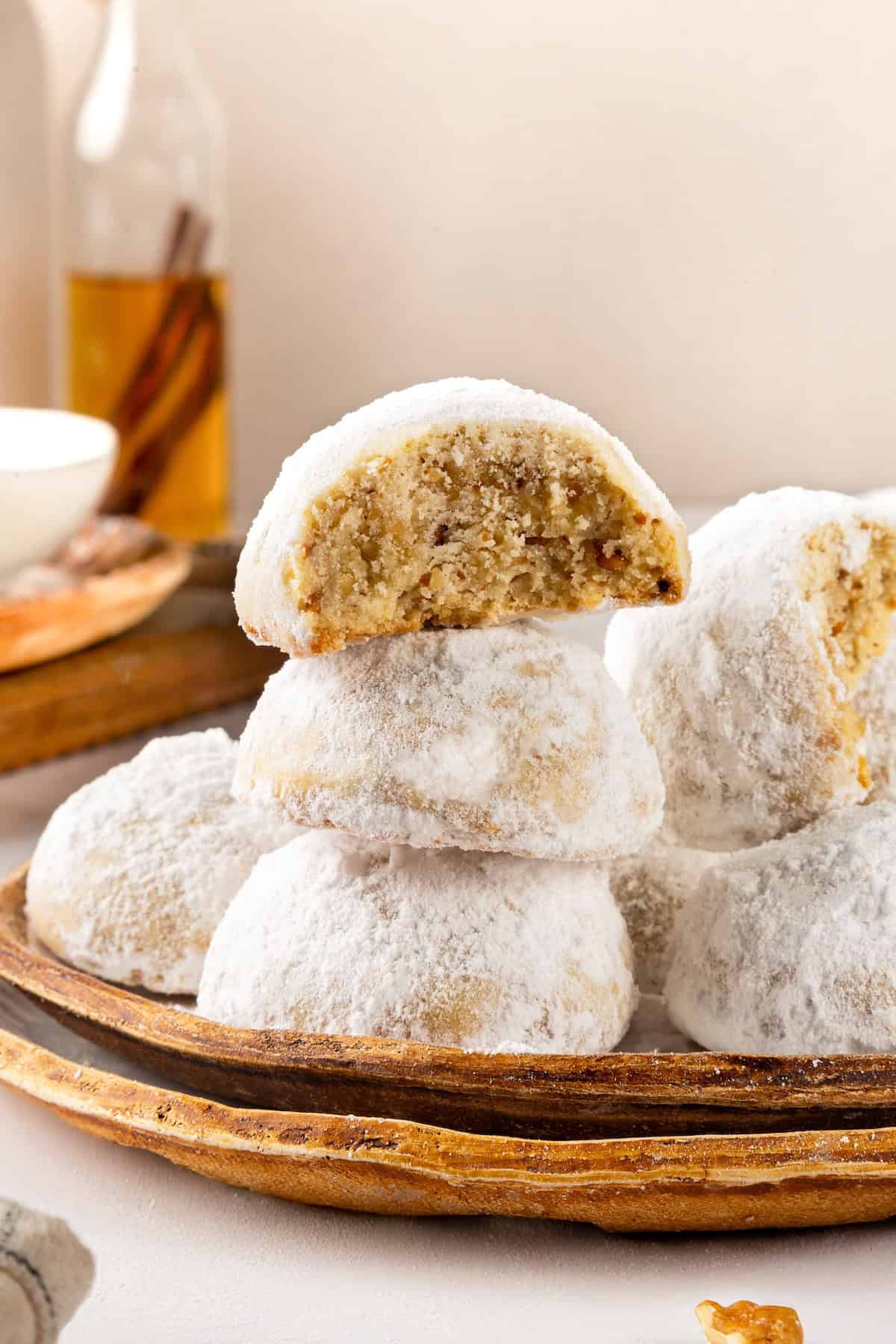 Buttery, melt-in-your-mouth and coated in powdered sugar, these vegan Mexican wedding cookies have everything you love about the original! Plate of Mexican wedding cookies, with one bitten to show interior.