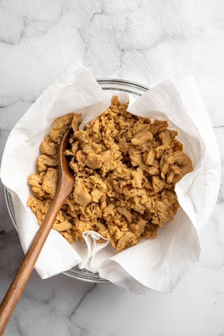 Soy curl "chicken" is a budget-friendly vegan swap for chicken that's crispy on the outside, full of savoury flavour, and super versatile! Draining soy curls in paper towel lined bowl.