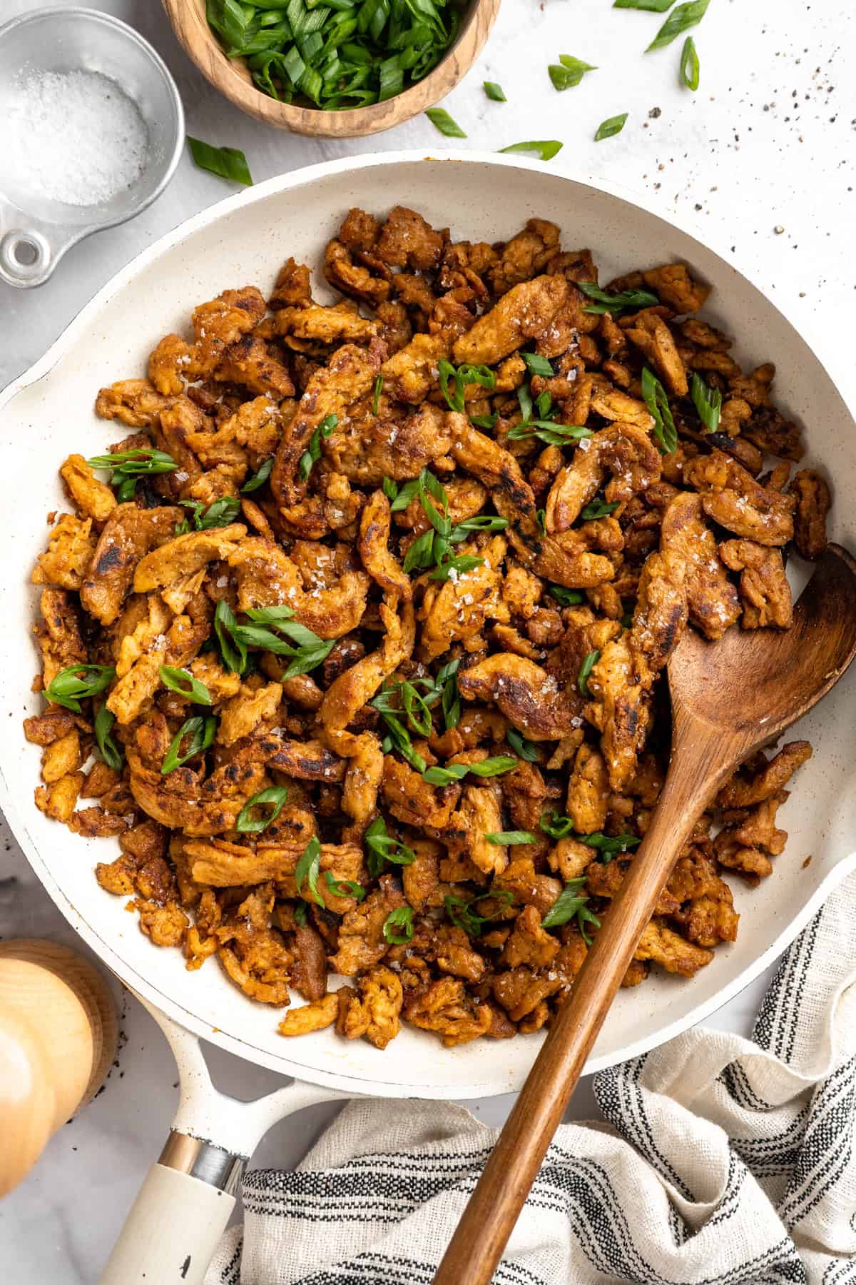 Soy curl "chicken" is a budget-friendly vegan swap for chicken that's crispy on the outside, full of savoury flavour, and super versatile! Skillet of soy curl chicken with wooden spoon.