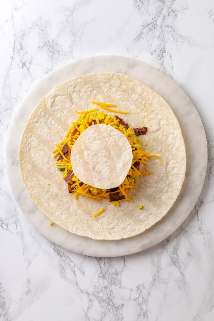 This vegan breakfast crunchwrap layers a crispy tortilla with tofu scramble, vegan bacon and creamy jalapeño sauce for a satisfying breakfast! Assembled breakfast crunchwrap before wrapping.