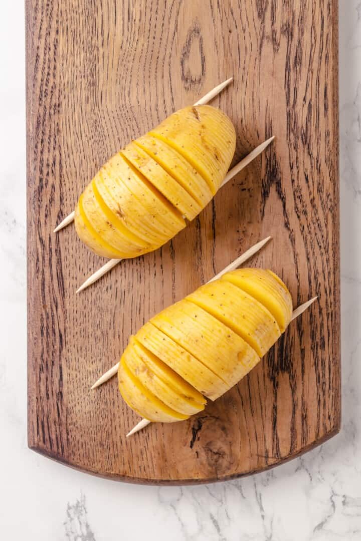 Hasselback potatoes are perfect for a party! The edges get crispy, the insides are tender, and garlic herb butter makes them irresistible. Sliced hasselback potatoes set on skewers.