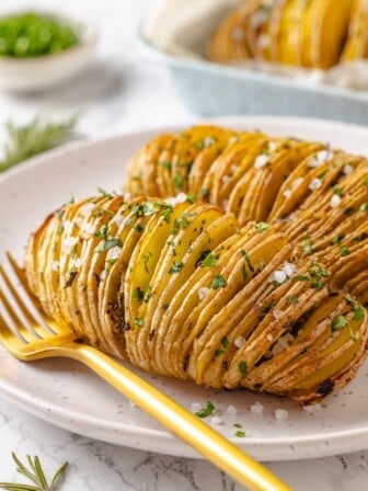 Two hasselback potatoes on plate.