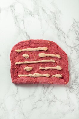 Dough for vegan salami in strips on marble countertop.