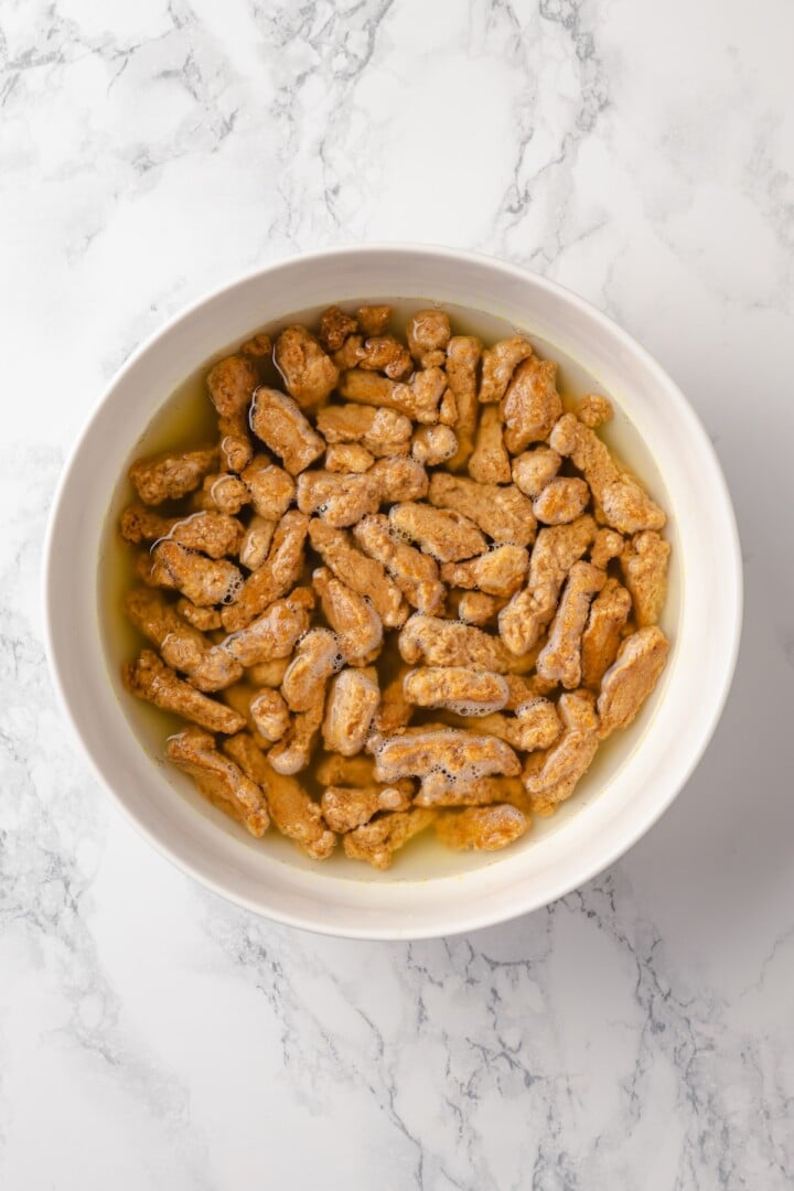 This vegan “chicken” Alfredo recipe is made with budget-friendly soy curls to replace the meat. It’s rich, garlicky and creamy. So good! Soy curls in bowl of water.